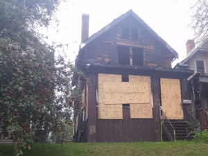 old damaged home with boards over windows.