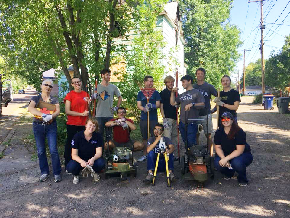 Group photo of VISTA members posing with yard tools after a day of service.